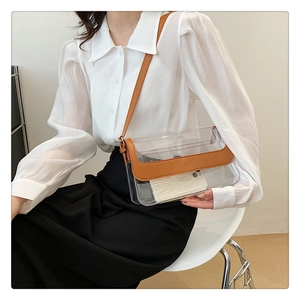 Détail d'un sac bandoulière transparent en PVC avec bordure en cuir marron et fine lanière