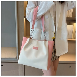 Détail du sac cabas bicolore avec bandoulière en cuir rose et étiquette fashion