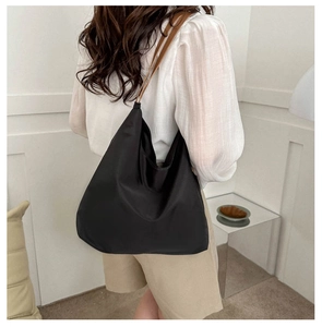 Detail of a large black oxford cloth tote bag with brown leather shoulder straps