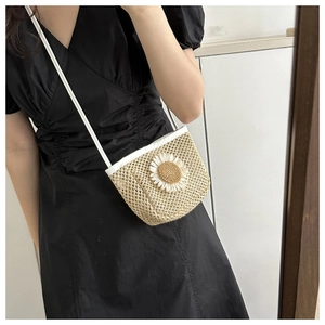 Detailed straw shoulder bag with a white daisy flower and a thin crossbody strap