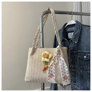 Detail of beige straw tote bag featuring herringbone weave and sunflower charm