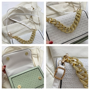 Detail view of woven texture, gold chain handle, and magnetic closure on the crossbody bag