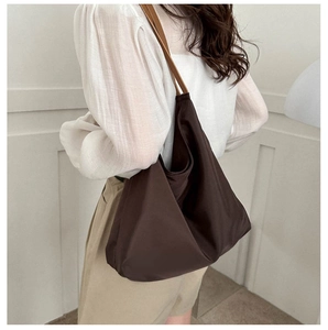 Detail of dark brown oxford tote bag with leather straps on model shoulder