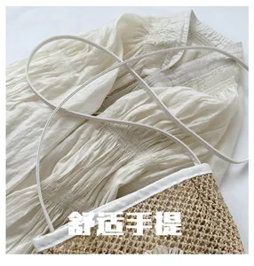 Detail of straw woven bucket bag with white trim and slim shoulder strap on shirt