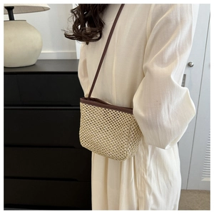 Detail of minimalist straw woven shoulder bag with dark brown leather straps for summer