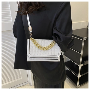 Detail of white geometric embossed flap bag with chunky gold chain on black blazer