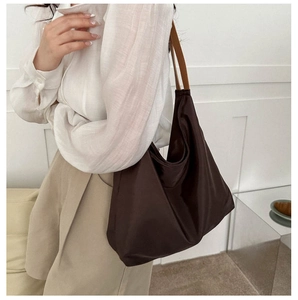 Detail of a large brown Oxford tote bag with premium leather handles on a female model