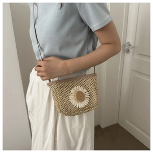 Close-up of beige woven straw bucket bag featuring a large white daisy flower decoration
