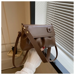 Détail d'un sac à main plissé caramel avec boucle carrée et finitions métalliques dorées