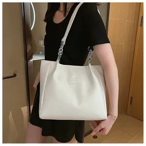 Détail du grand cabas blanc avec chaîne argentée et étiquette de mode sur le cuir