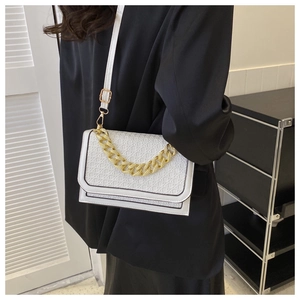 Detailed view of the embossed white crossbody bag with decorative gold chain strap
