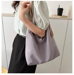 Detail of lavender nylon tote bag with brown leather straps shown on model shoulder