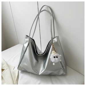 Detail of silver metallic tote bag with fluffy white monster pendant on white fabric