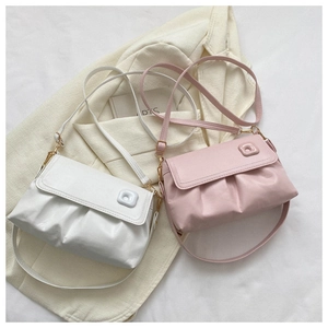 Détail de sacs à bandoulière froncés élégants en blanc et rose sur un blazer beige