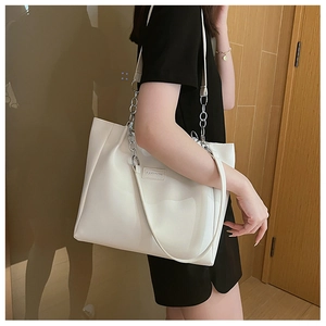 Détail du cabas blanc avec poignée chaîne argentée et écusson logo FASHION sur le modèle