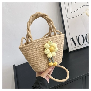 Detail of woven straw bucket bag featuring 3D floral accent and thick braided handle