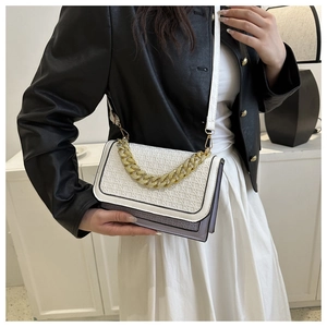 Detail of contrast stitch handbag featuring woven flap and chunky gold chain strap
