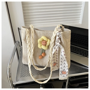 Detail of woven straw tote bag with yellow flower charm and decorative silk scarf