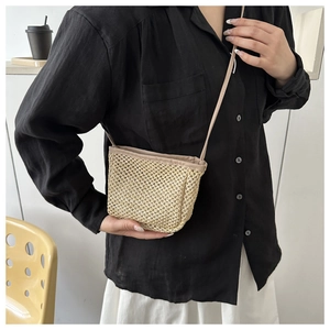Detailed view of women's woven straw bucket bag with delicate hollow crochet texture