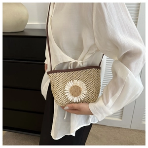 Detail of straw crossbody bag with white daisy flower on modern white shirt model