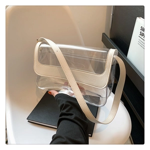 Détail d'un sac bandoulière en PVC transparent avec bordure en cuir crème et rabat carré