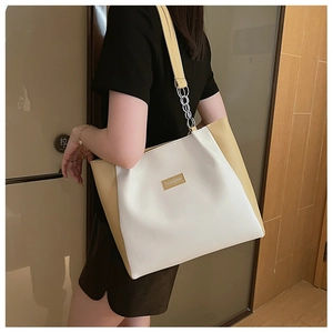 Détail du sac cabas en cuir blanc et jaune avec bandoulière chaîne argentée sur l'épaule