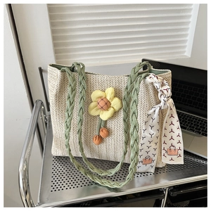 Close-up of beige woven straw tote bag with green straps and yellow floral ornament