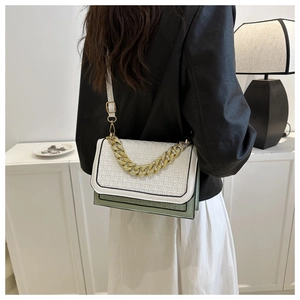 Detail of color-block crossbody bag with woven texture and gold chain strap worn by model