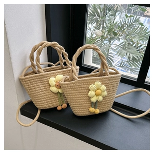 Detail of hand-woven straw bucket bag featuring 3D floral accents and woven top handles