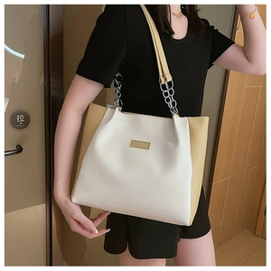 Détail du sac cabas bicolore avec bandoulière chaîne et étiquette Fashion porté