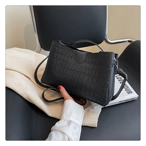 Close-up of black crocodile pattern tote bag with fine texture on a leather seat