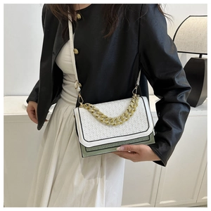Detail of color-block crossbody bag featuring woven texture and chunky gold chain strap
