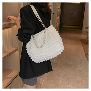 Macro detail of white bubble textured tote bag with floral pearl chain strap design