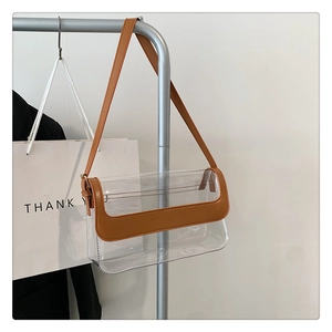 Détail du sac rectangulaire en PVC transparent avec bordure en cuir marron et bandoulière