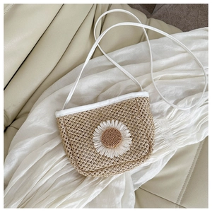 Close-up of woven straw bag with white daisy flower detail and leather strap