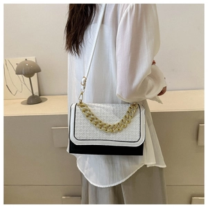 Detail of color-block crossbody bag with bold gold chain and woven texture design