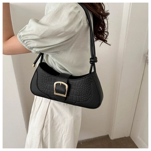 Détail du sac porté épaule noir à motif crocodile avec boucle dorée et bandoulière nouée