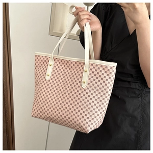 Close-up of pink and beige geometric tote bag with white handles and gold rivets