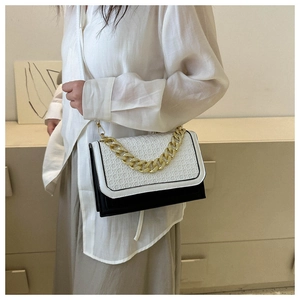 Detail of black and white crossbody bag with woven texture and gold chain strap