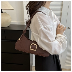 Détail du sac baguette marron foncé effet crocodile avec boucle dorée porté à l'épaule