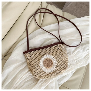 Detailed close-up of khaki straw woven crossbody bag with a large white daisy flower applique
