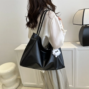 Minimalist black faux leather large tote bag with cute white plush charm on model