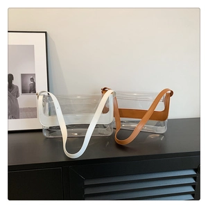 Détail de sacs bandoulière en PVC transparent avec bordures en similicuir blanc et marron