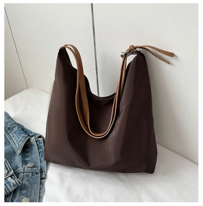 Detail of large brown nylon tote bag with contrasting leather straps on white background