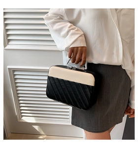 Detail of quilted two-tone makeup case with silver metal handle and dual zipper design