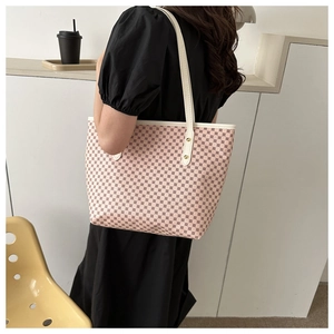 Chic beige tote bag with geometric pattern and white leather straps worn by a model