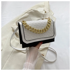 Detail of black and white contrast handbag with woven texture and gold chain link