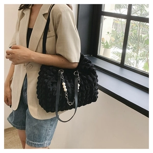 Close-up of black bubble textured tote bag with silver chain and white pearl accessory