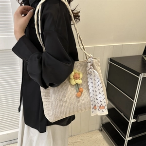 Woven straw tote bag with yellow flower charm and decorative scarf for summer