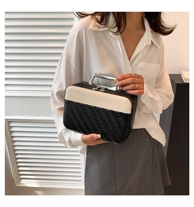 Detail of black quilted makeup bag with cream leather top and gold petal zipper